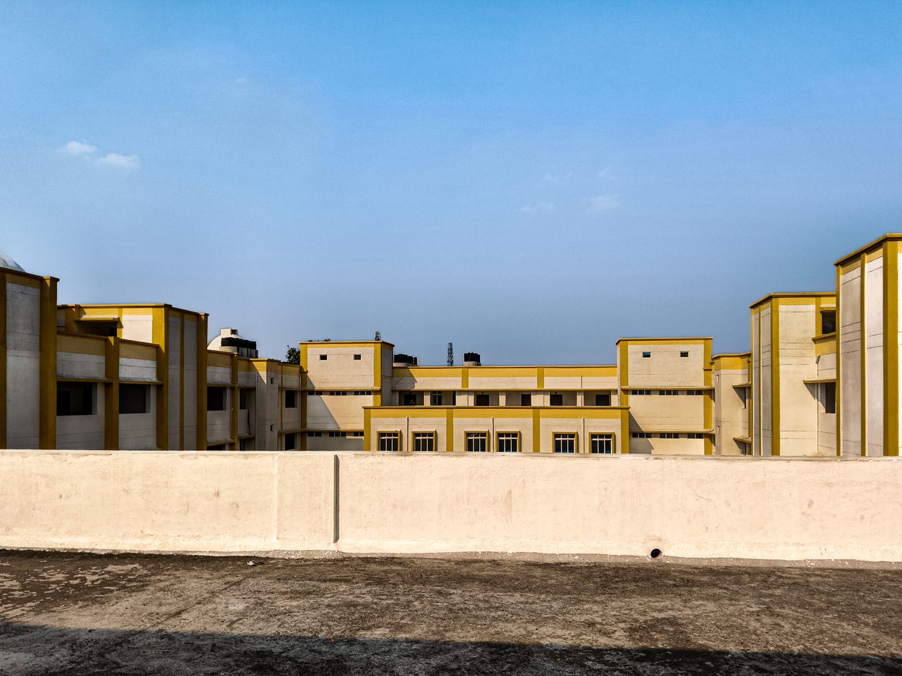 Contemporary building with geometric design in warm sunlight, set against a clear blue sky.