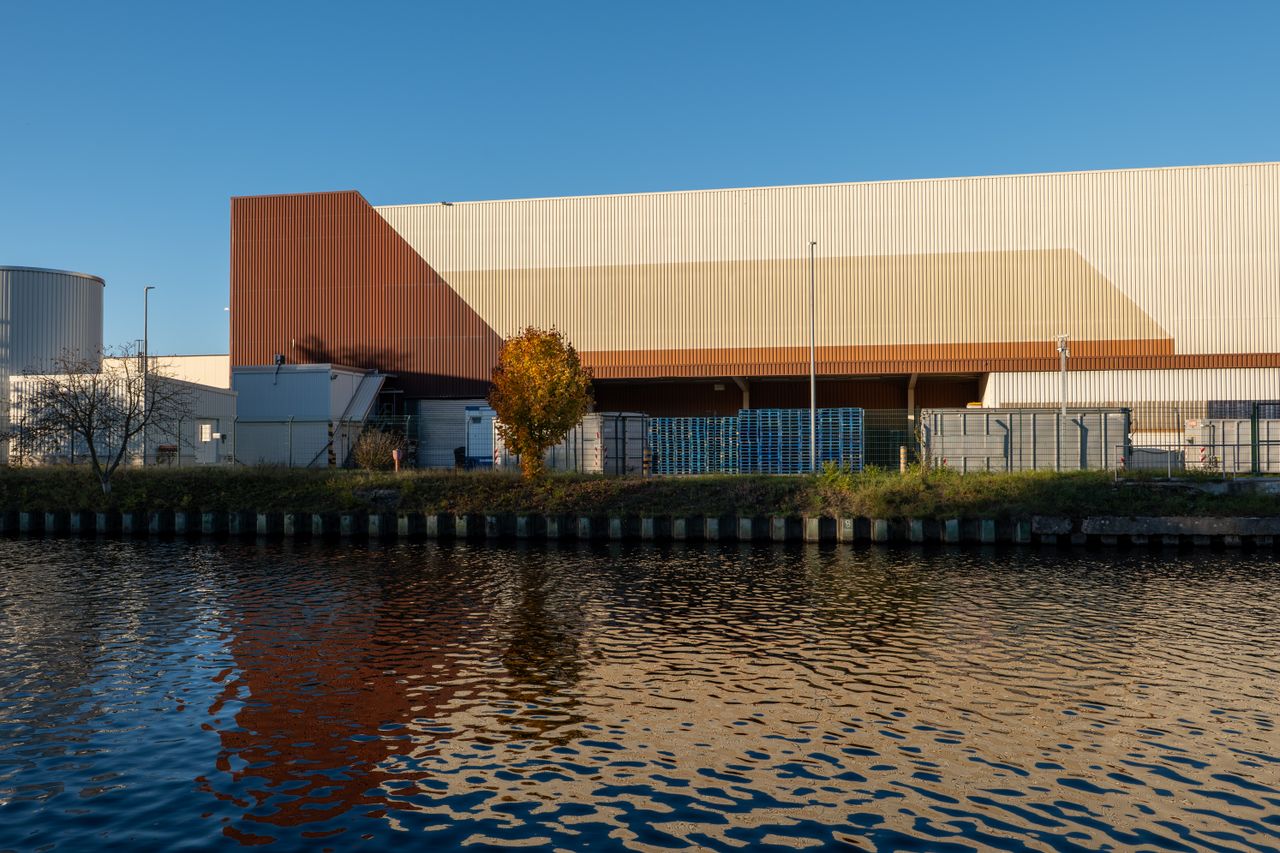 Modern industrial warehouse building reflected in calm river water.