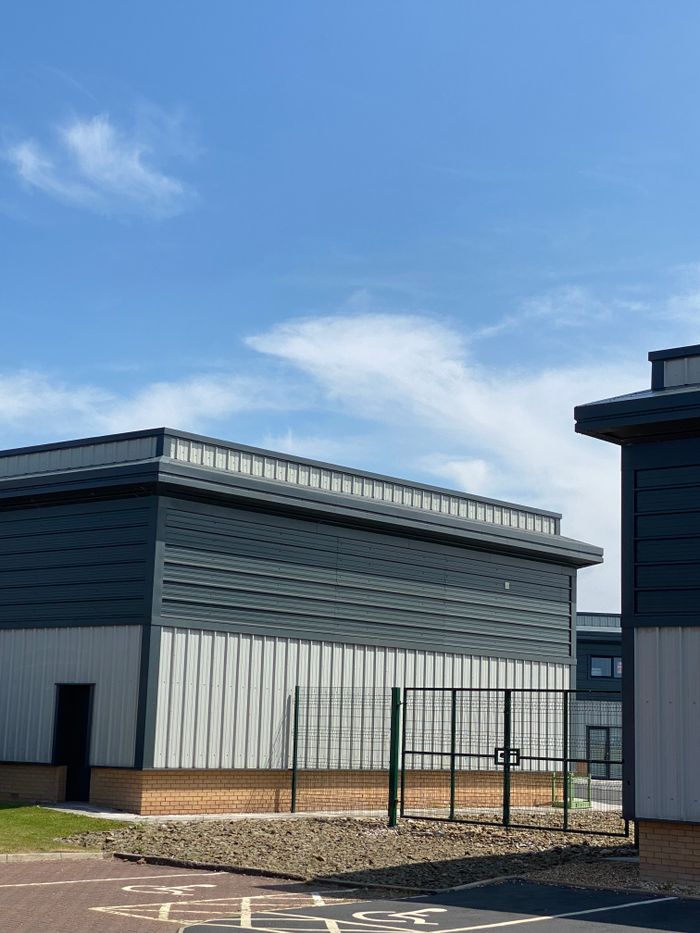 Modern industrial warehouse building under a clear blue sky, featuring sleek design.